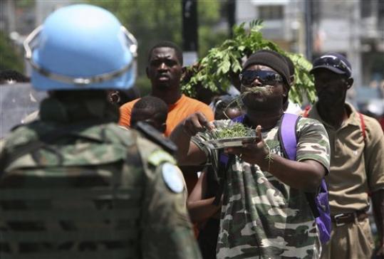 Haiti, dimostrante mangia erba di fronte ad un casco  blu dell'ONU